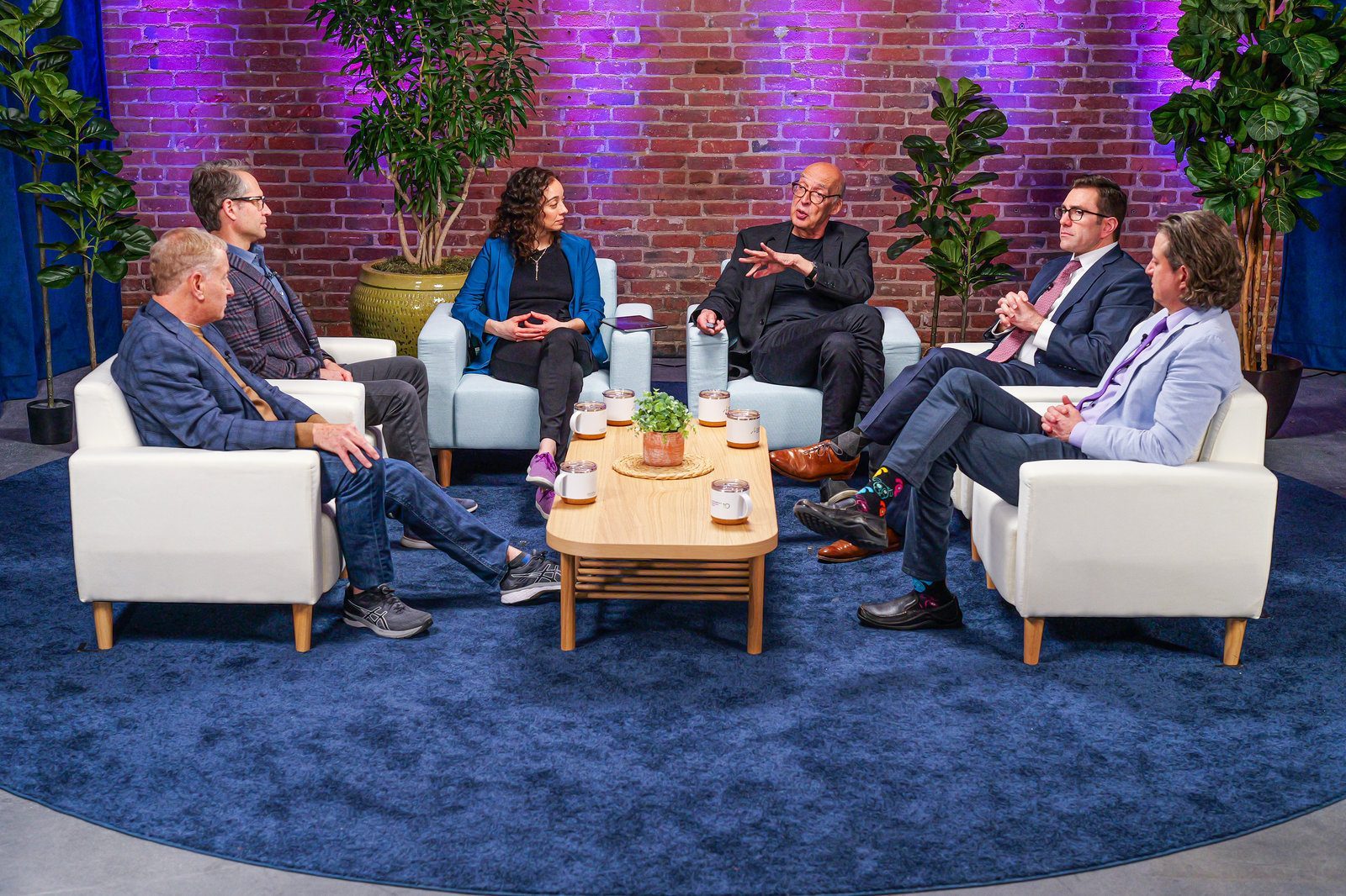 A panel discussion on a studio set with purple brick and blue carpet
