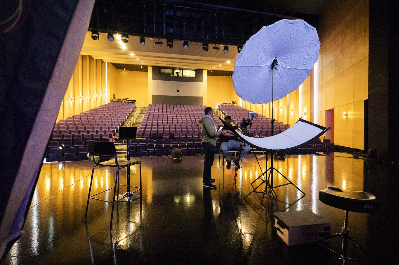 Umbrella light on stage in a golden-lit theatre, set for a shoot
