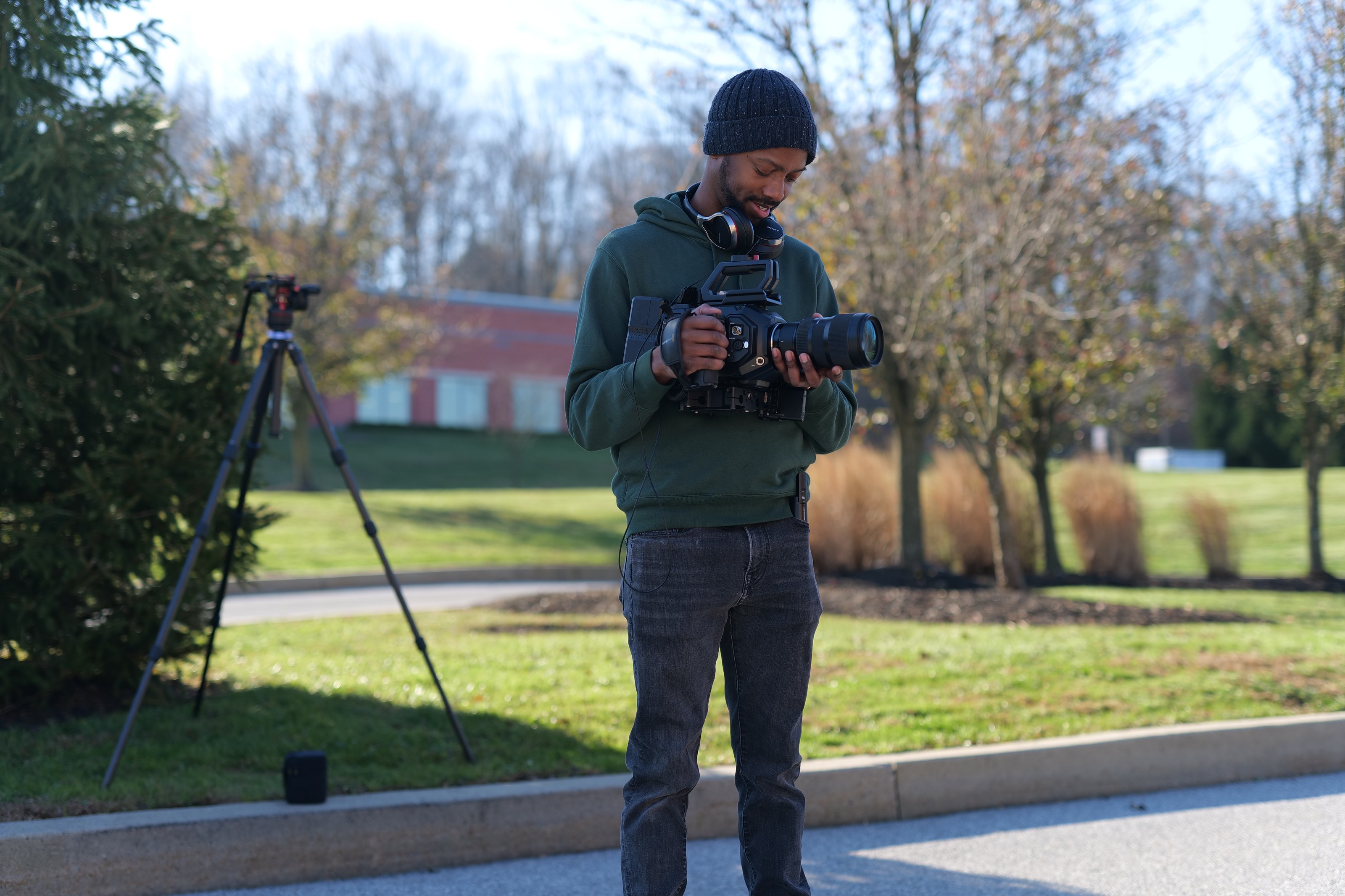 Davone filming outdoors beside a tripod on a campus shoot