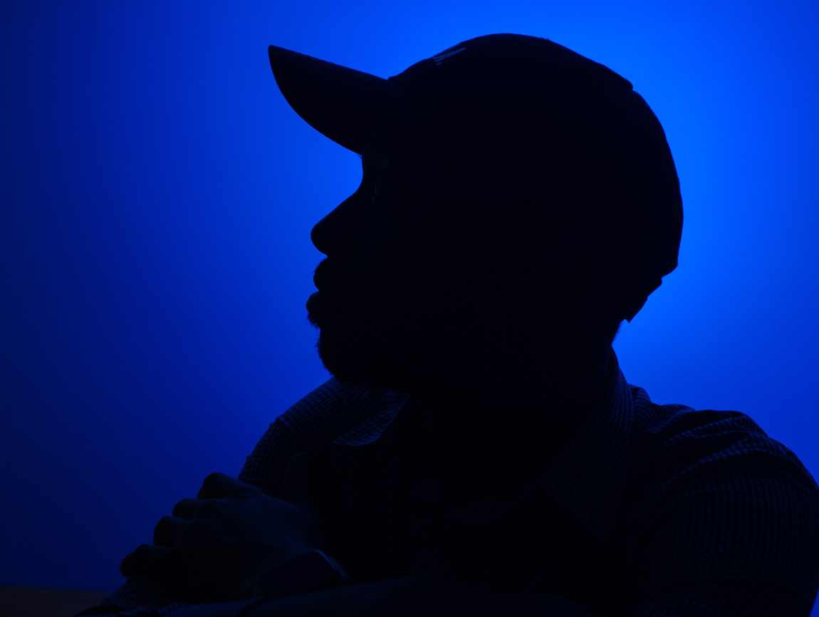 Davone in profile, silhouetted in blue studio light